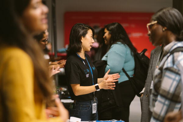 Photos of two women looking at one another and speaking. Other women in the foreground and background speaking to one another.